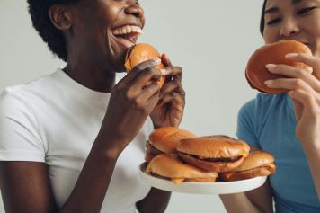 Two friends share laughter and delicious burgers, capturing a moment of joy and togetherness.