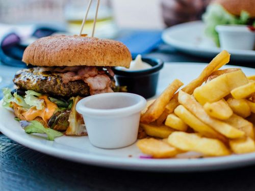 Close-up of a juicy burger and crispy fries served with sauces, perfect for a hearty meal.